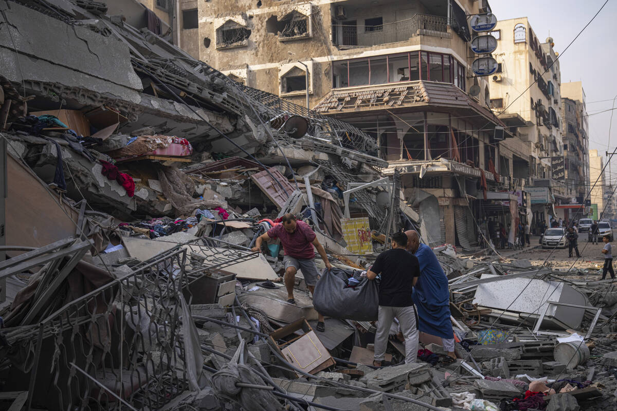 Palestinians scour the debris from the rubble of a building after it was struck by an Israeli a ...