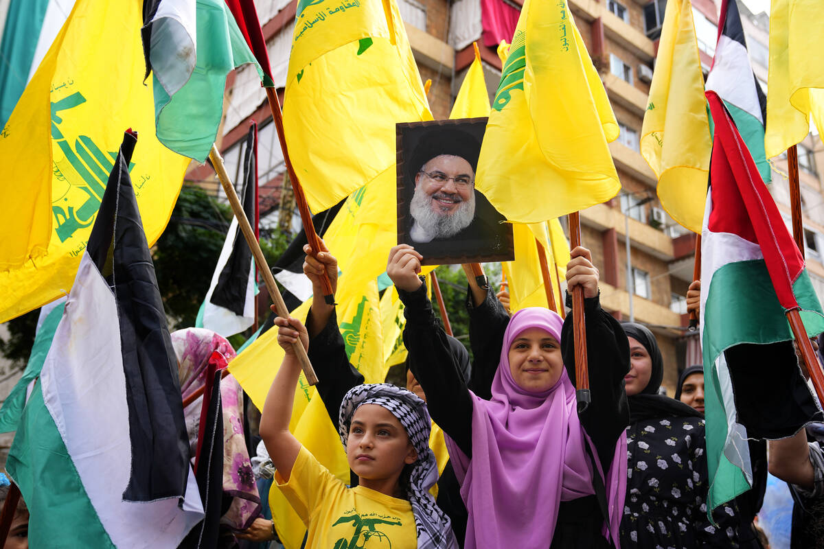 A Hezbollah supporter holds up a portrait of Hezbollah leader Sayyed Hassan Nasrallah as others ...