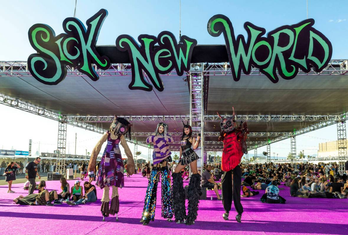 Stilt walkers in costume await photo opportunities during the Sick New World festival at the La ...