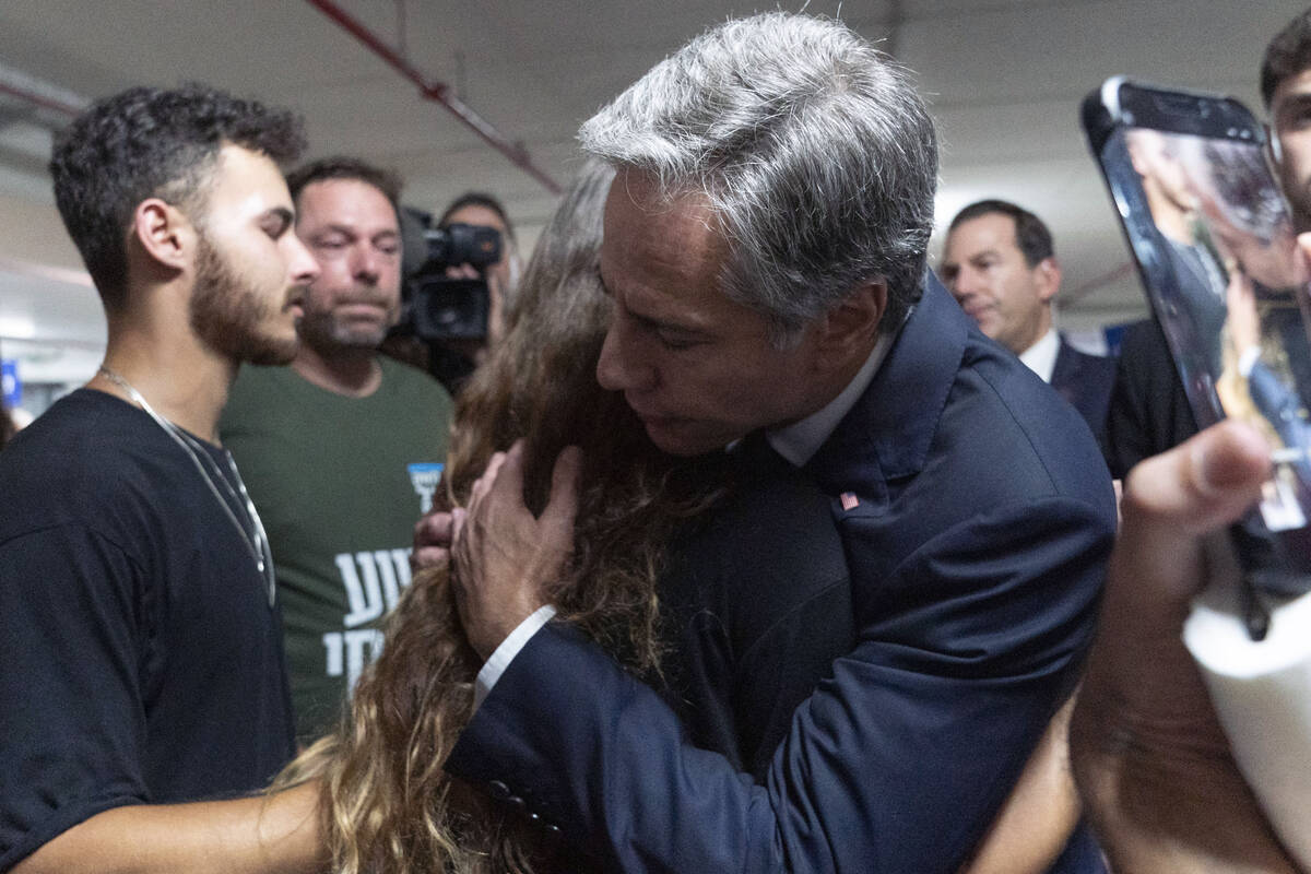 U.S. Secretary of State Antony Blinken is embraced by Lior Gelbaum, right, 24, a dual U.S.-Isra ...