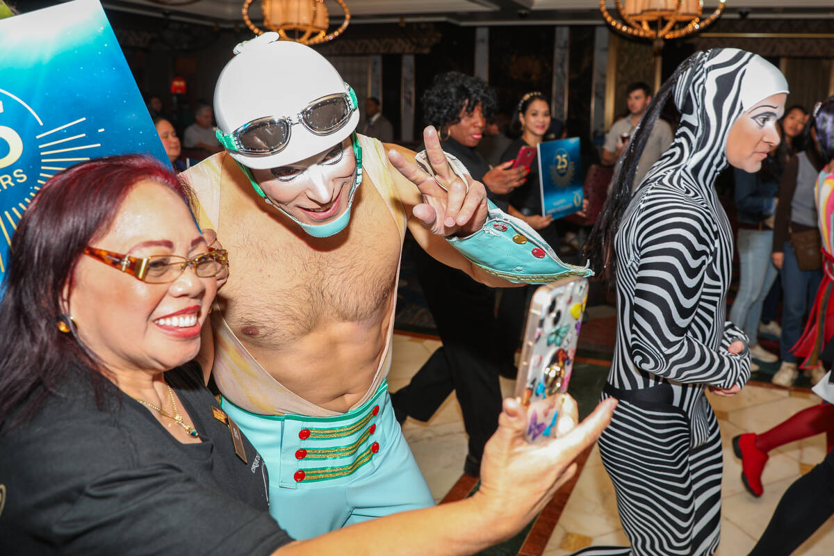 A Cirque du Soleil performer and usher pose for a selfie as they walk through the Bellagio as p ...