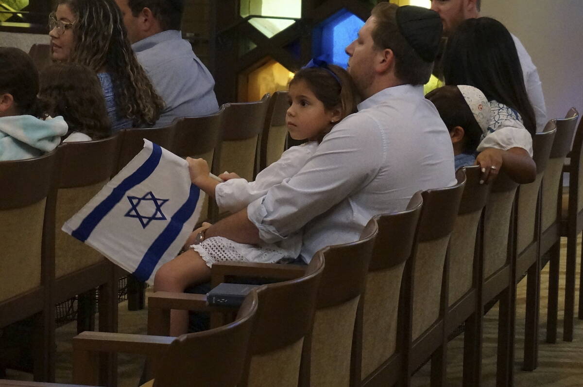 A family with Israel flags attends Shabbat services at Temple Beth Sholom in Miami Beach, Fla., ...