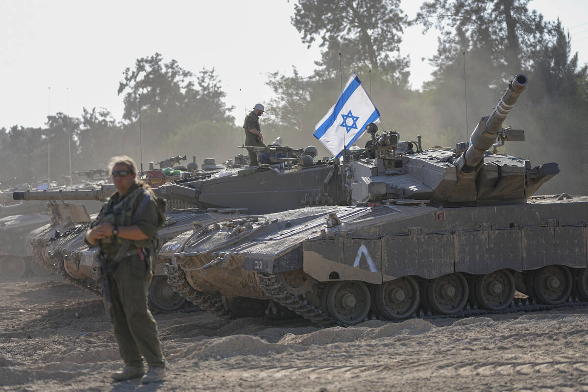 Israeli soldiers work on a tank at a staging area in southern Israel near the border with the G ...
