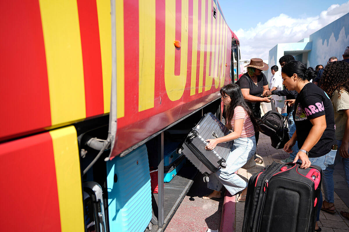 Israelis load their belongings onto a bus as they evacuate from the southern Israeli town of Sd ...