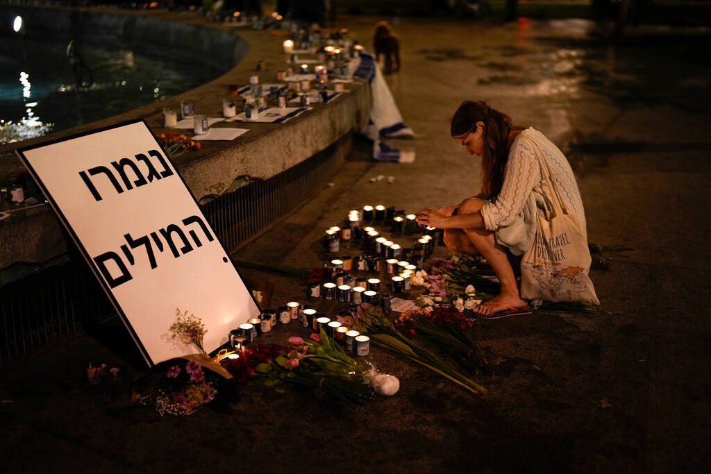 A woman lights candles in honor of victims of the Hamas attacks during a vigil at Dizengoff squ ...