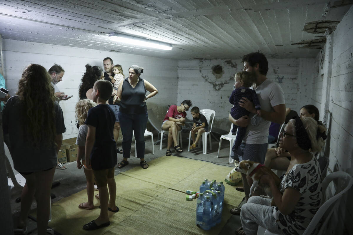 Israelis take cover in a shelter as a siren sounds a warning of incoming rockets fired from the ...