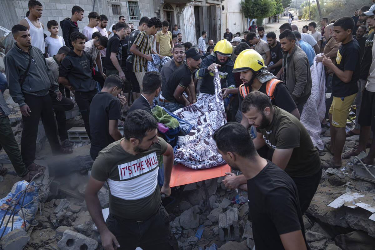 Palestinians carry a person wounded in Israeli airstrikes in Khan Younis, Gaza Strip, Monday, O ...