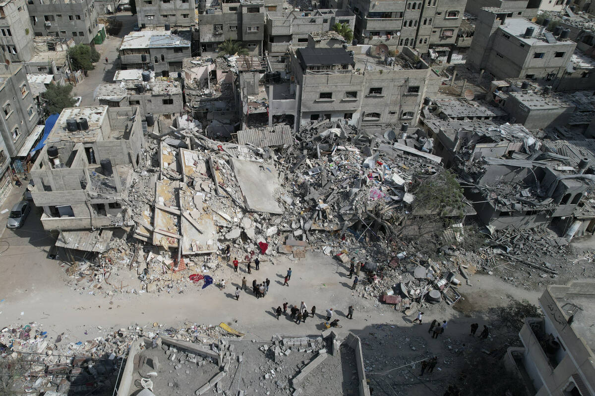 Palestinians stand by the building destroyed in an Israeli airstrike in Nuseirat camp in the ce ...