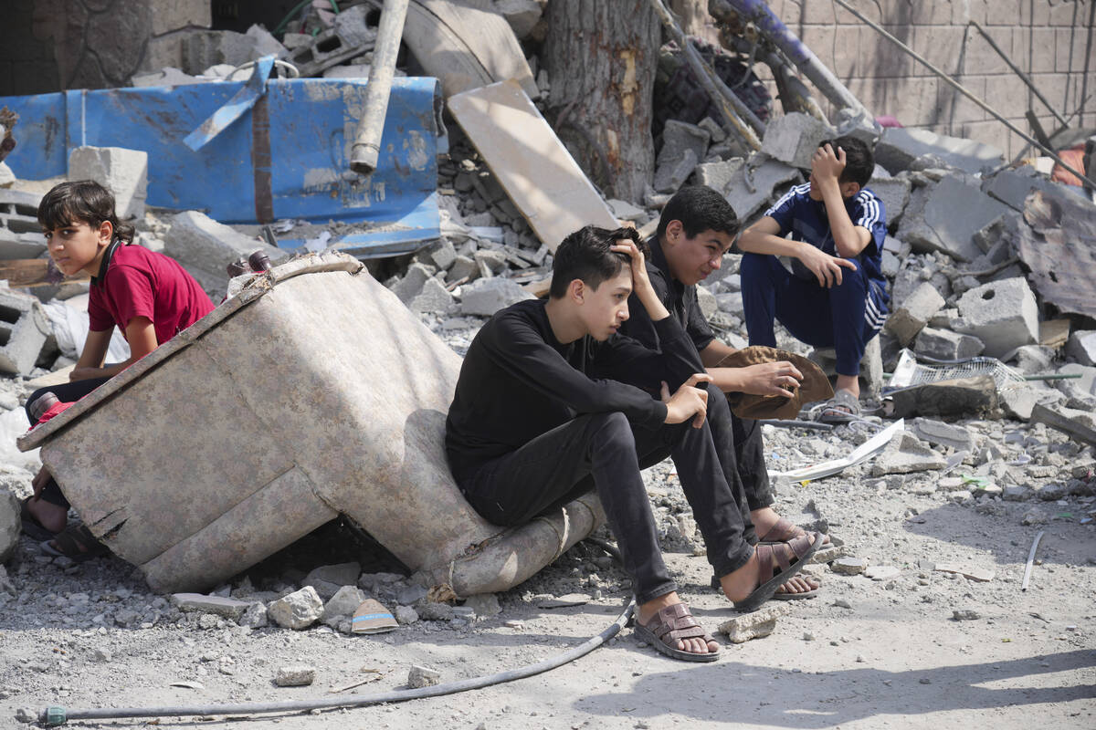 Palestinian boys sit on the rubble of a building destroyed in an Israeli airstrike in Nuseirat ...