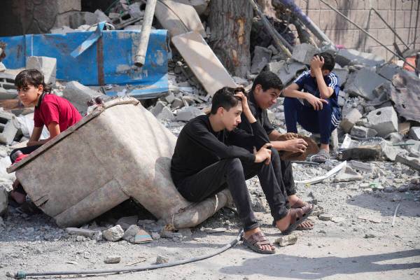 Palestinian boys sit on the rubble of a building destroyed in an Israeli airstrike in Nuseirat ...