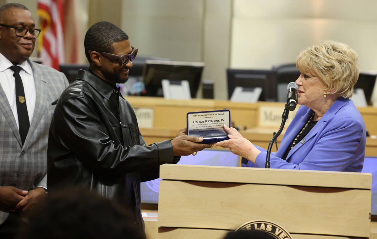 Usher, center, receives a key to the City of Las Vegas from Mayor Carolyn Goodman as Councilman ...