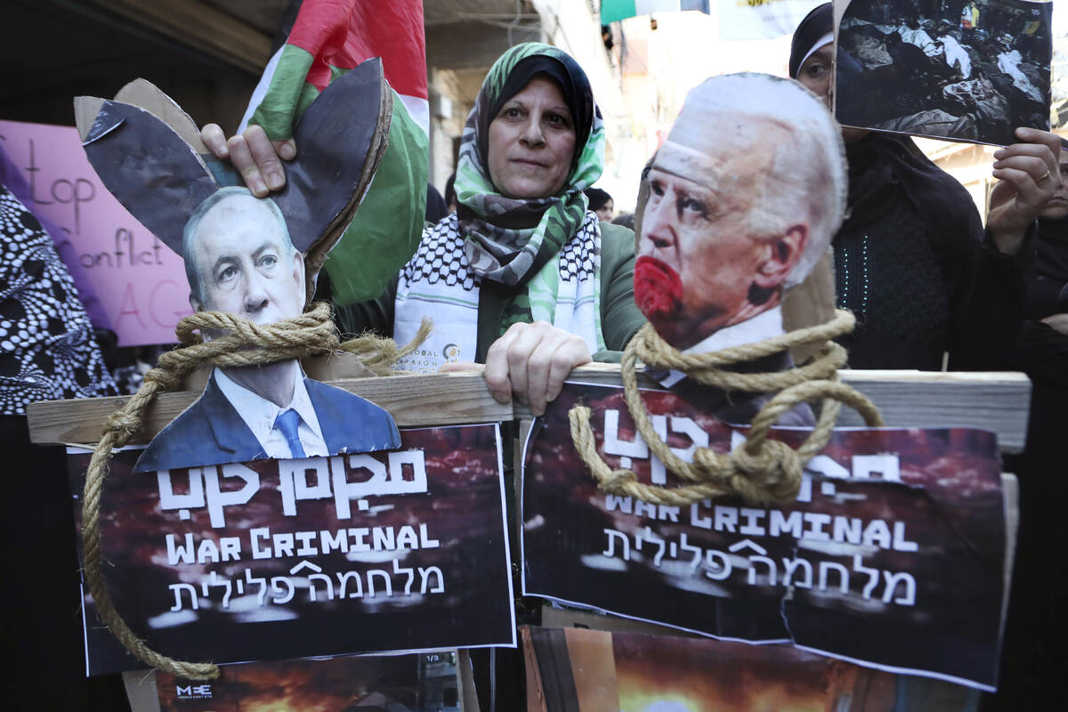 A Palestinian protester hold placards against U.S. President Joe Biden, right, and Israeli Prim ...