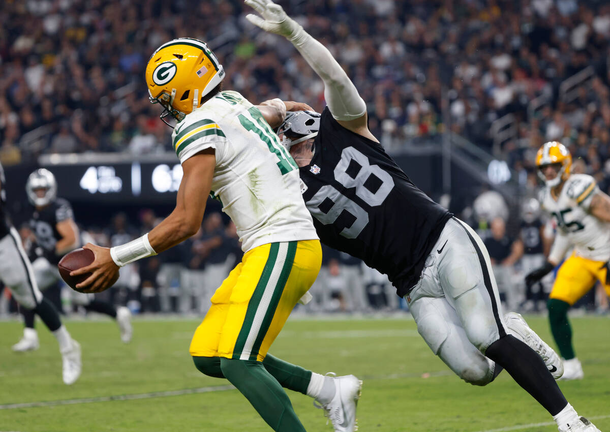 The Green Bay Packers quarterback Jordan Love (10) tries to avoid a tackle from Raiders defensi ...