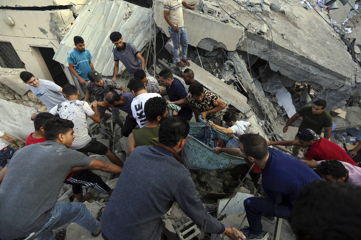 Palestinians carry a body of a dead person found under the rubble of a destroyed building of a ...