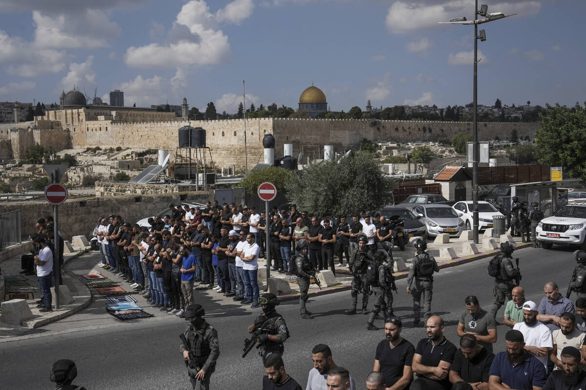 Palestinian worshippers pray outside Jerusalem's Old City while Israeli forces stand guard, Fri ...
