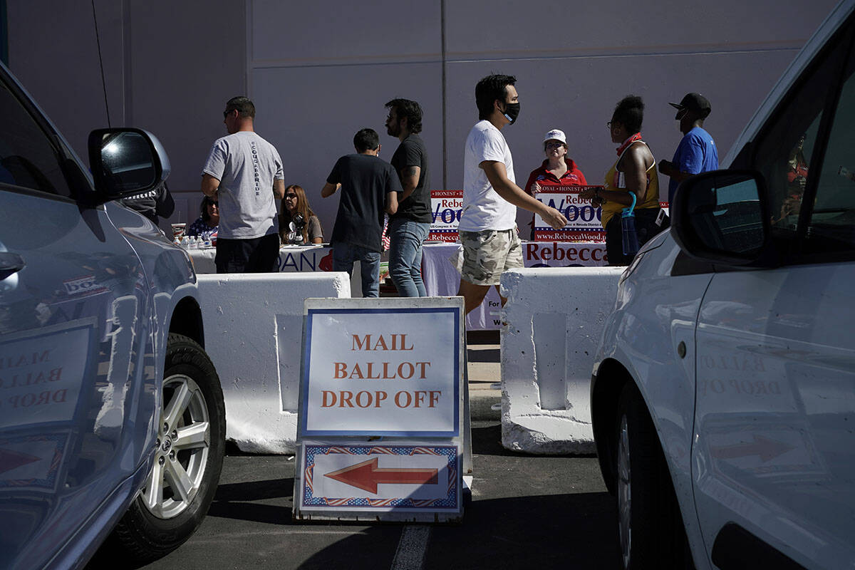 In this June 9, 2020, file photo, a sign indicates where mail ballots may dropped off as people ...