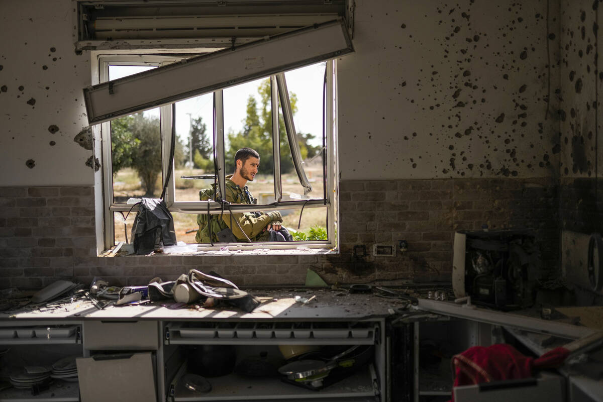 An Isreal soldier patrols next to a house damaged by Hamas militants at Kibbutz Kissufim in sou ...