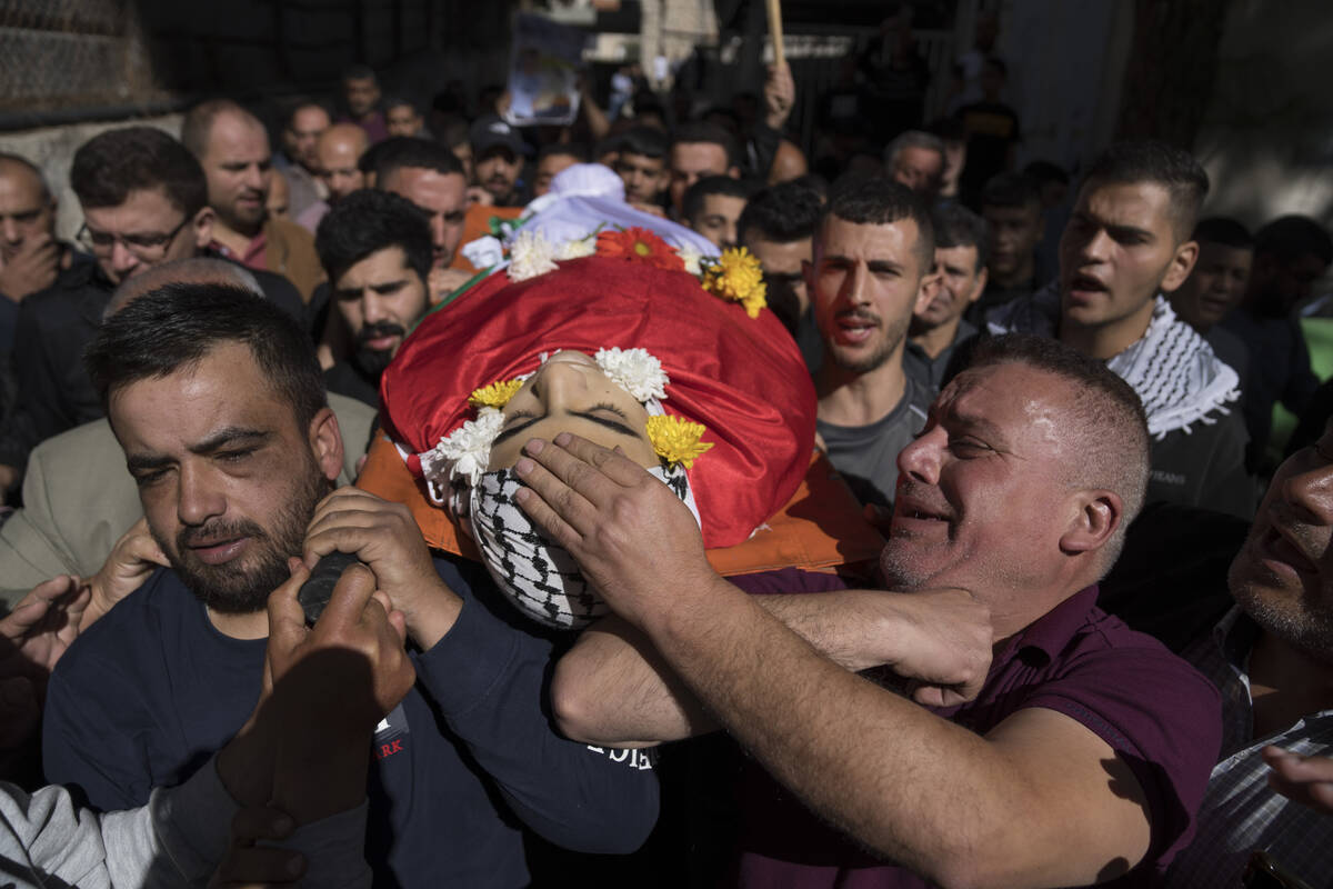 Eyad al-Soos, right carries the body of his son Sohaib al-Soos, 15, during his funeral in the W ...