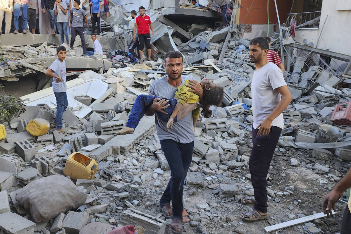 Palestinian carries a child killed in an airstrike on the buildings of Abu Asad family in Deir ...