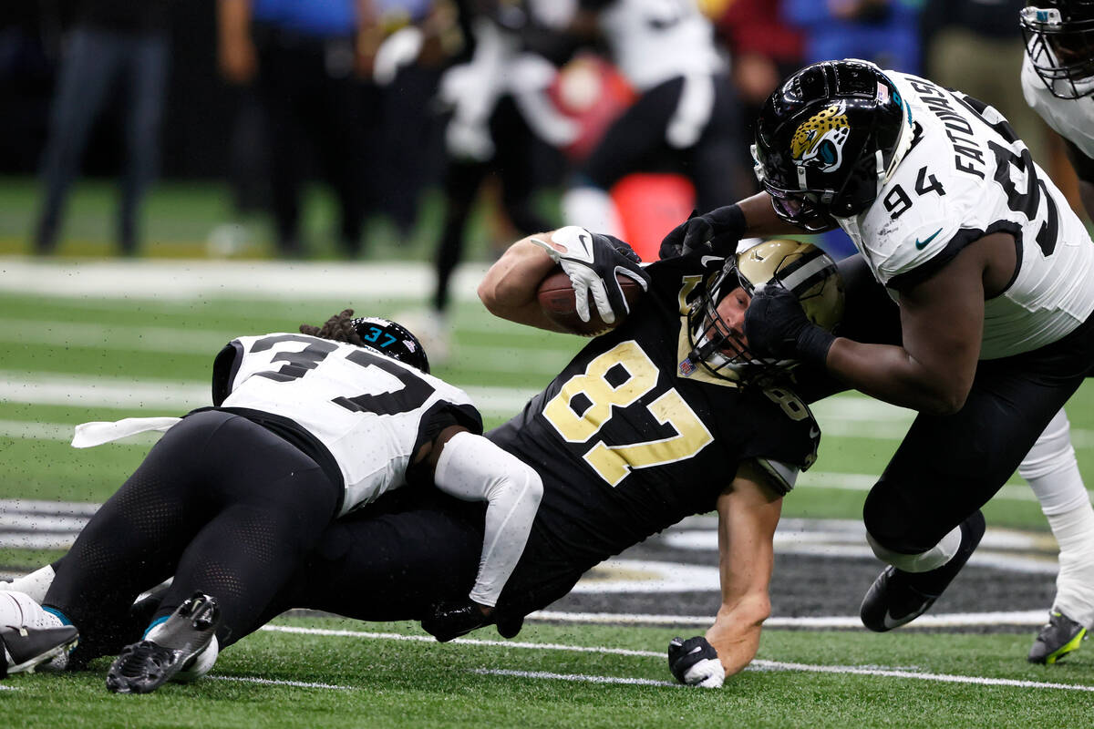 New Orleans Saints tight end Foster Moreau (87) is tackled by Jacksonville Jaguars cornerback T ...