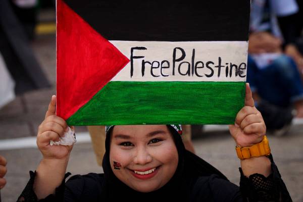 A Malaysian Muslim holds a poster representing the Palestinian flag during a rally to show her ...