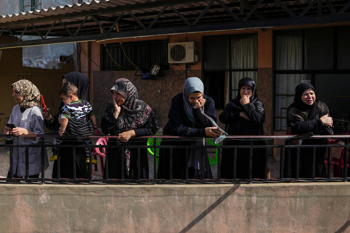 Women mourn as they watch from their balcony the funeral procession of Hezbollah fighter, Bilal ...
