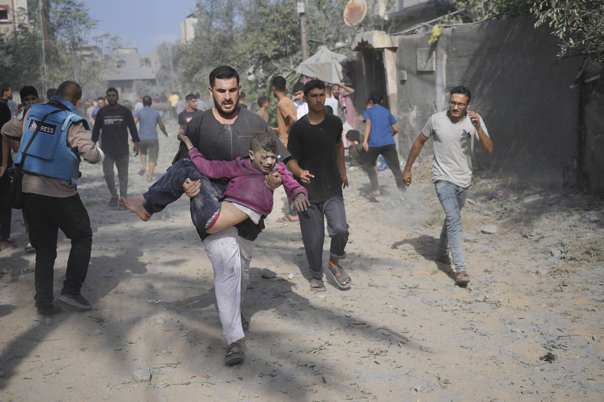 A Palestinian carries a boy wounded during the Israeli bombardment of the Gaza Strip in Deir Al ...