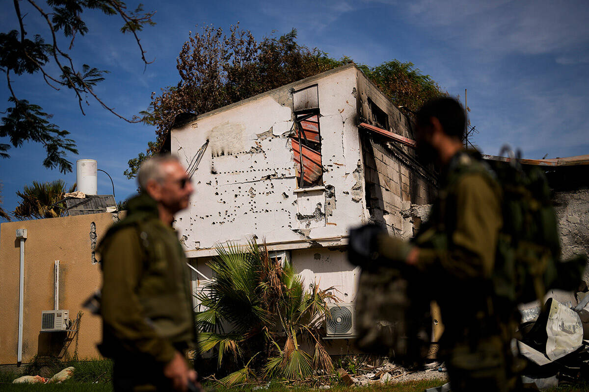 Soldiers walk next to a house damaged by Hamas militants at Kibbutz Kissufim in southern Israel ...