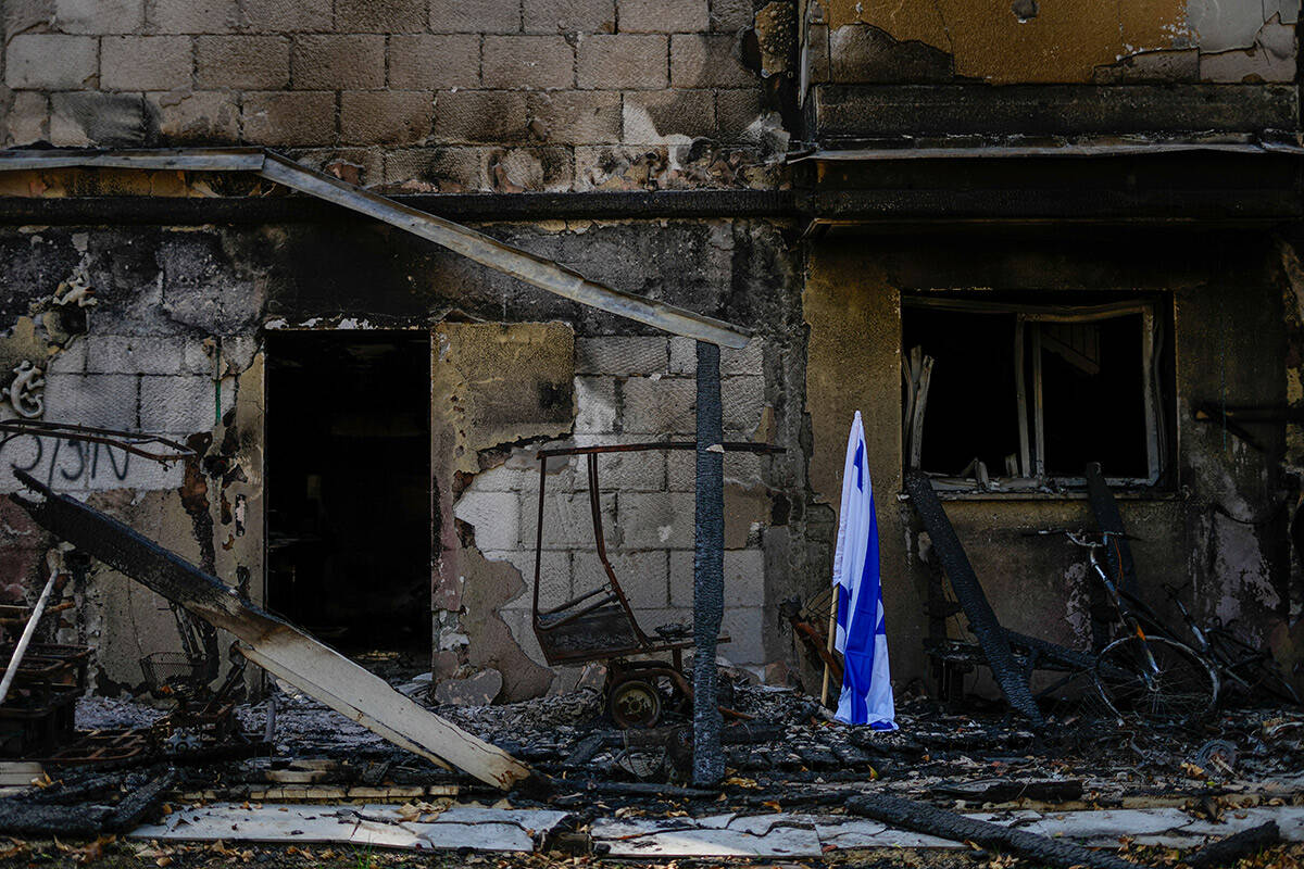 An Israeli flag is placed next to a house destroyed by Hamas militants in Kibbutz Be'eri, Israe ...