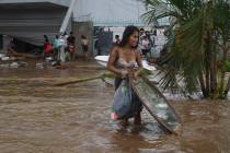 A woman walks away with stuff she took from a furniture store after Hurricane Otis ripped throu ...