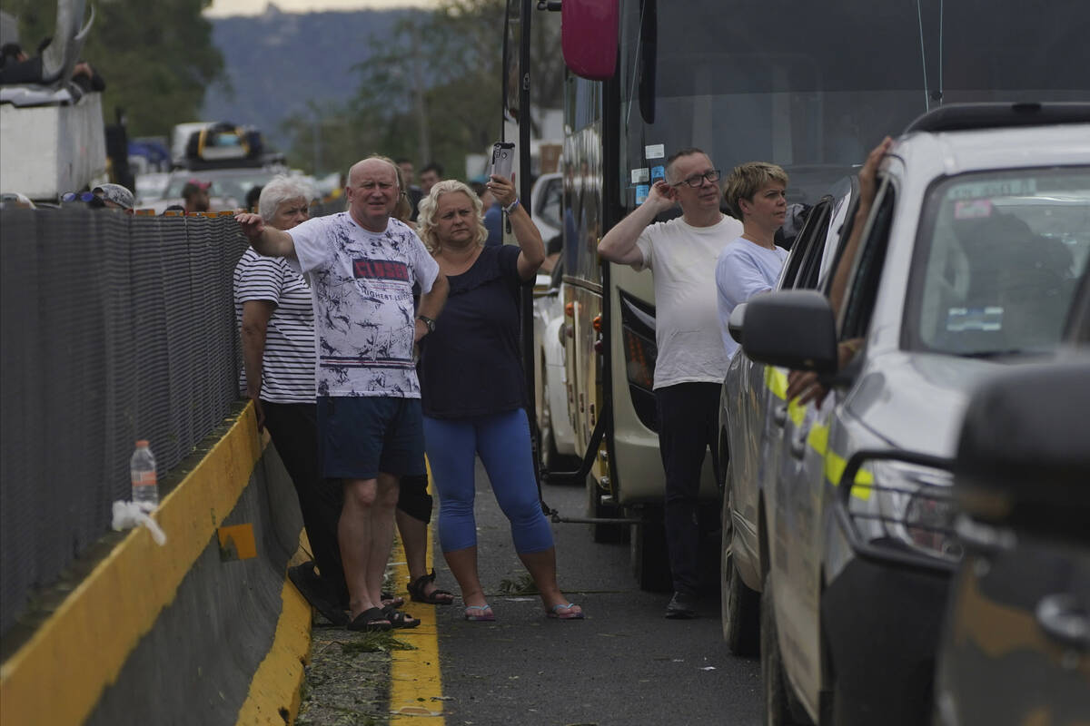 People wait outside their cars as they wait for repair crews to clear the roads after Hurricane ...