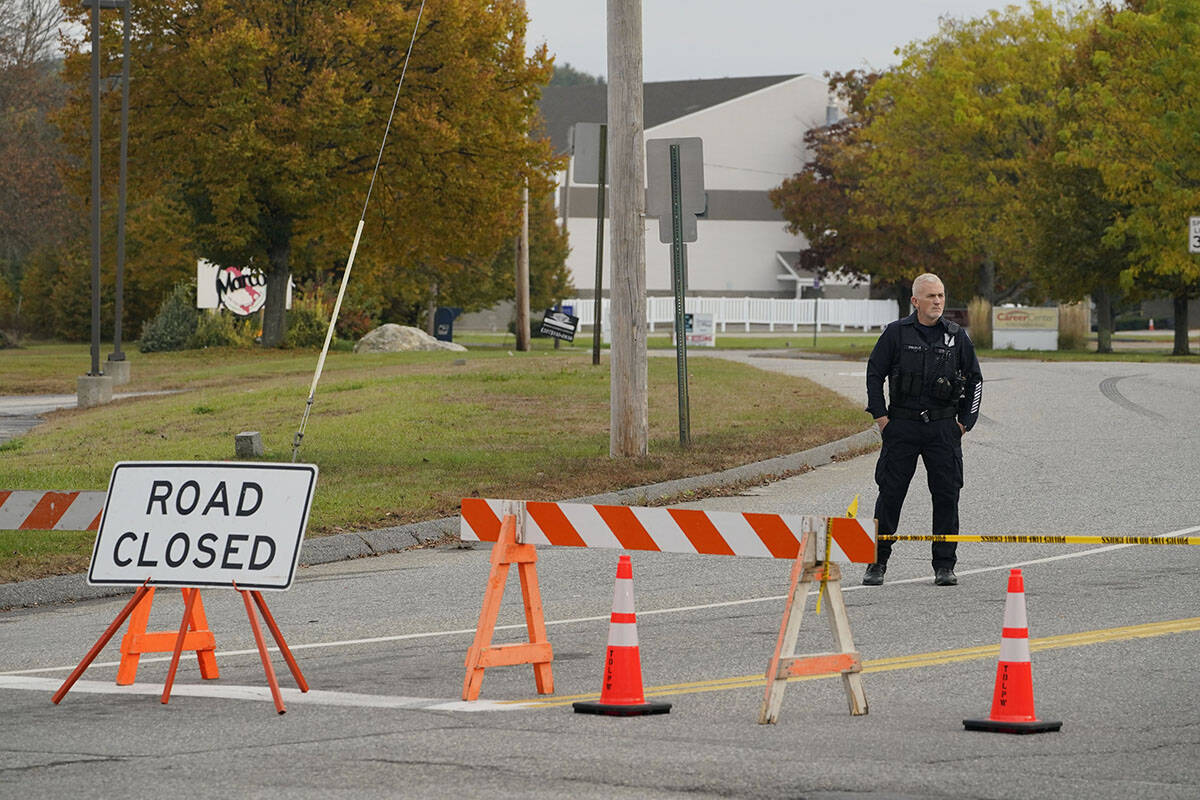 A police officer stands at a road closure near a bowling alley, seen in background, Thursday, O ...