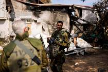 Soldiers walk next to a house damaged by Hamas militants at Kibbutz Kissufim in southern Israel ...