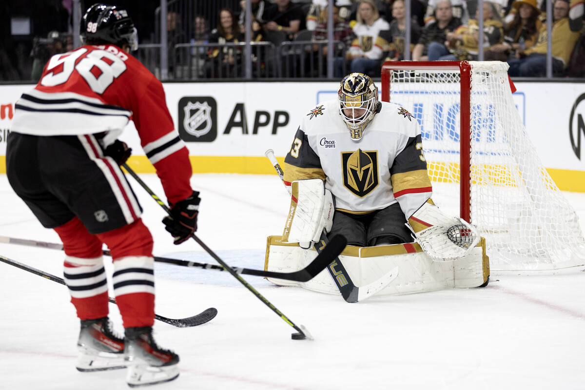Golden Knights goaltender Adin Hill (33) prepares to save a shot by Blackhawks center Connor Be ...