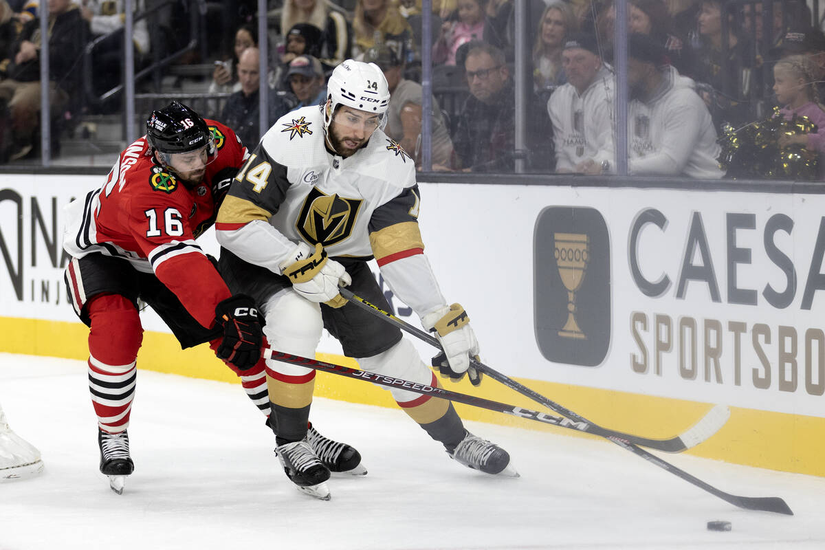 Golden Knights defenseman Nicolas Hague (14) skates with the puck while Blackhawks center Jason ...