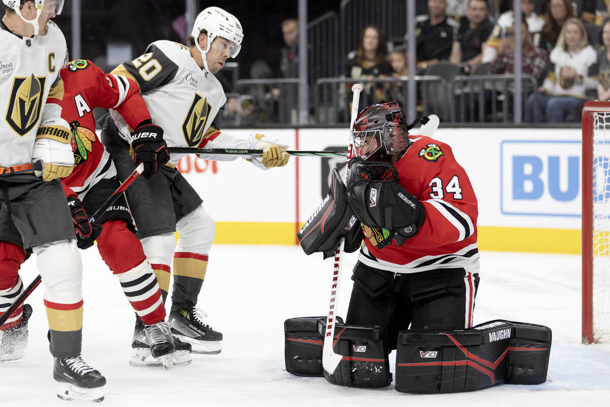 Blackhawks goaltender Petr Mrazek (34) saves the puck with his mask while Golden Knights center ...