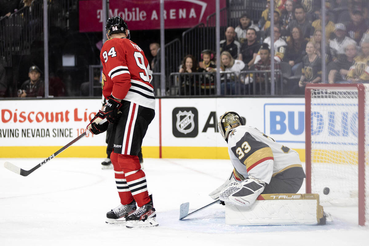 Golden Knights goaltender Adin Hill (33) and Blackhawks right wing Corey Perry (94) watch the p ...