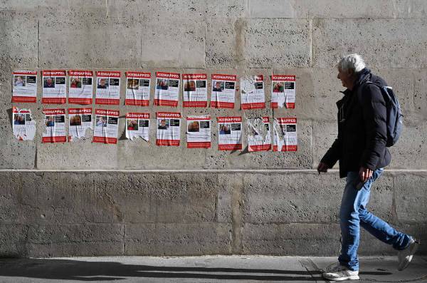 A man walks past placards, showing recently abducted or missing Israelis, to symbolise young ho ...