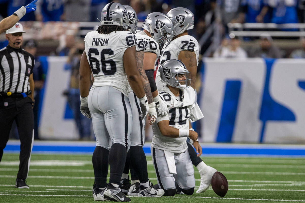 Raiders quarterback Jimmy Garoppolo (10) tosses the football to the side with guard Dylan Parha ...