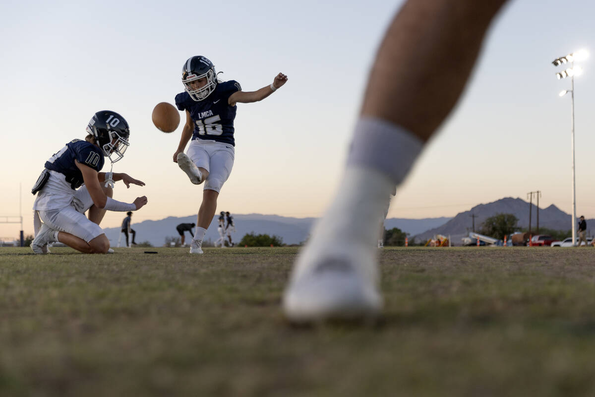 Kicker Gracie Rhodes (16) warms up with a ball held by teammate Brendyn Downing (10) before the ...