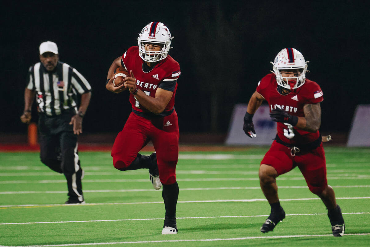 Liberty quarterback Tyrese Smith (11) runs the ball as Liberty running back Isaiah Lauofo runs ...