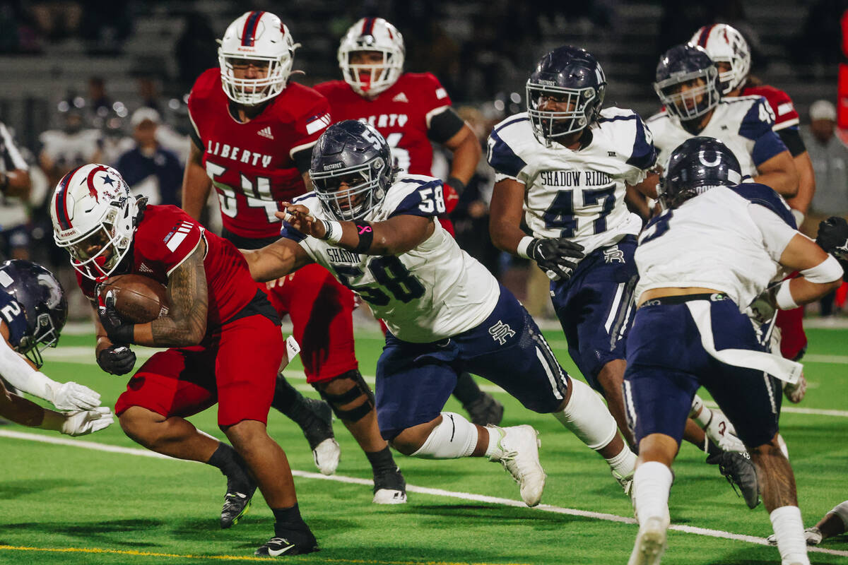 Liberty running back Isaiah Lauofo (3) runs the ball as Shadow Ridge defensive tackle Miki Pool ...