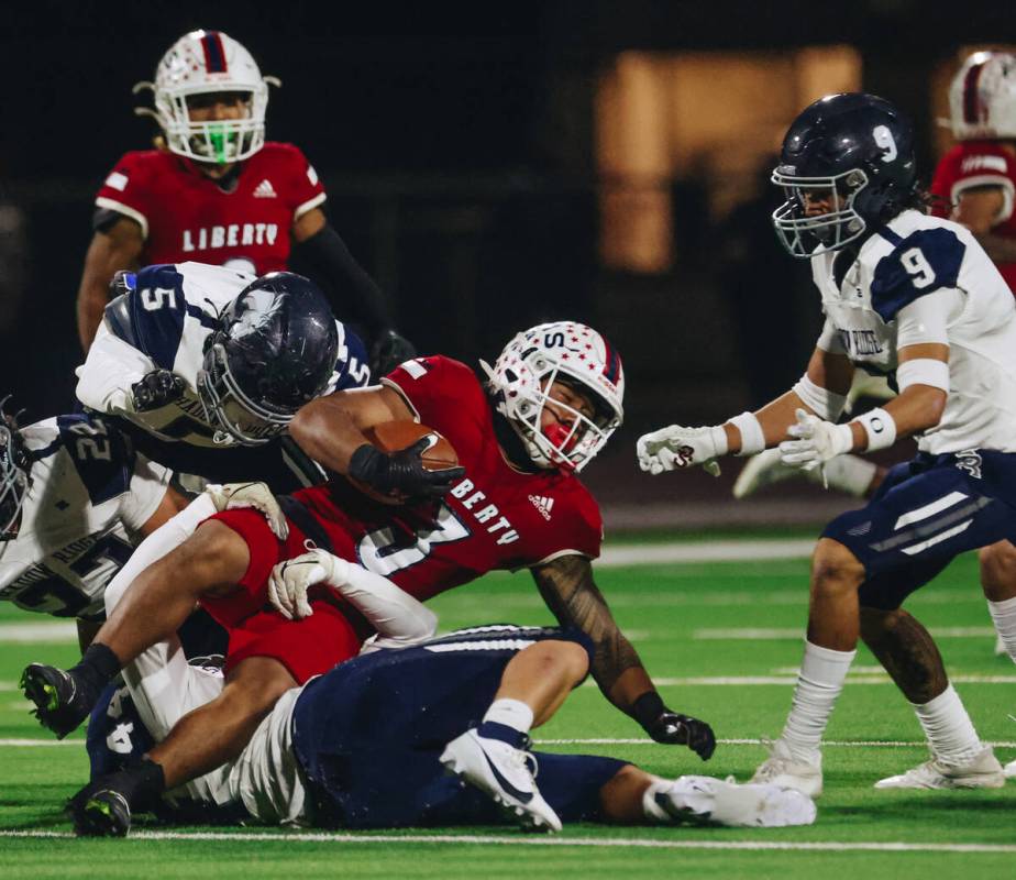 Liberty running back Isaiah Lauofo (3) tries to keep on his feet as he carries the ball past Sh ...