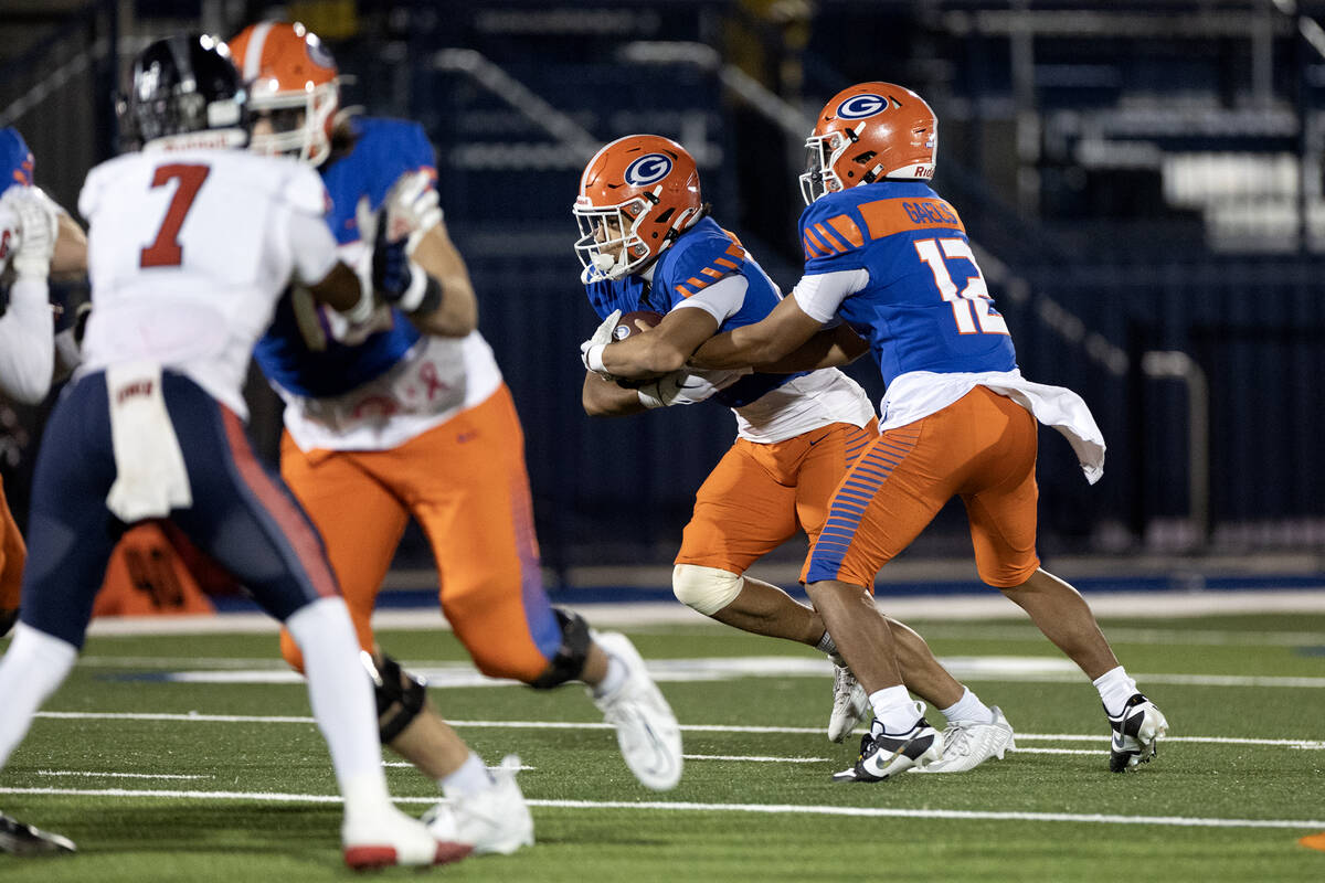 Bishop Gorman quarterback Micah Alejado (12) hands the ball off to Bishop Gorman running back M ...