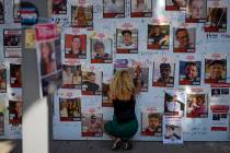 A woman writes on a photo of people kidnapped during the Oct. 7 Hamas bloody cross-border attac ...
