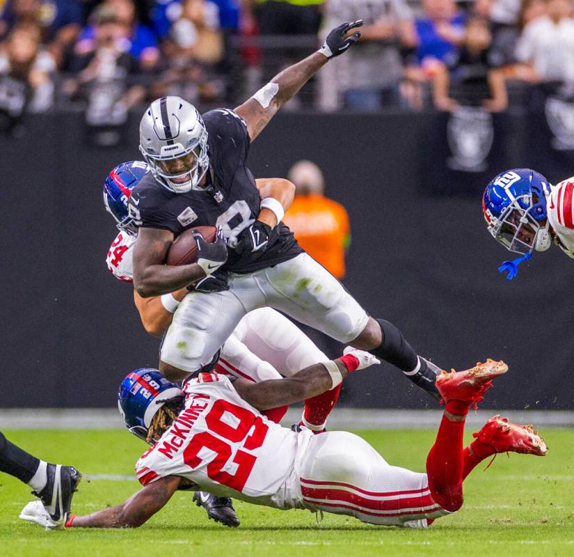 Raiders running back Josh Jacobs (8) is grabbed by New York Giants safety Dane Belton (24) whil ...