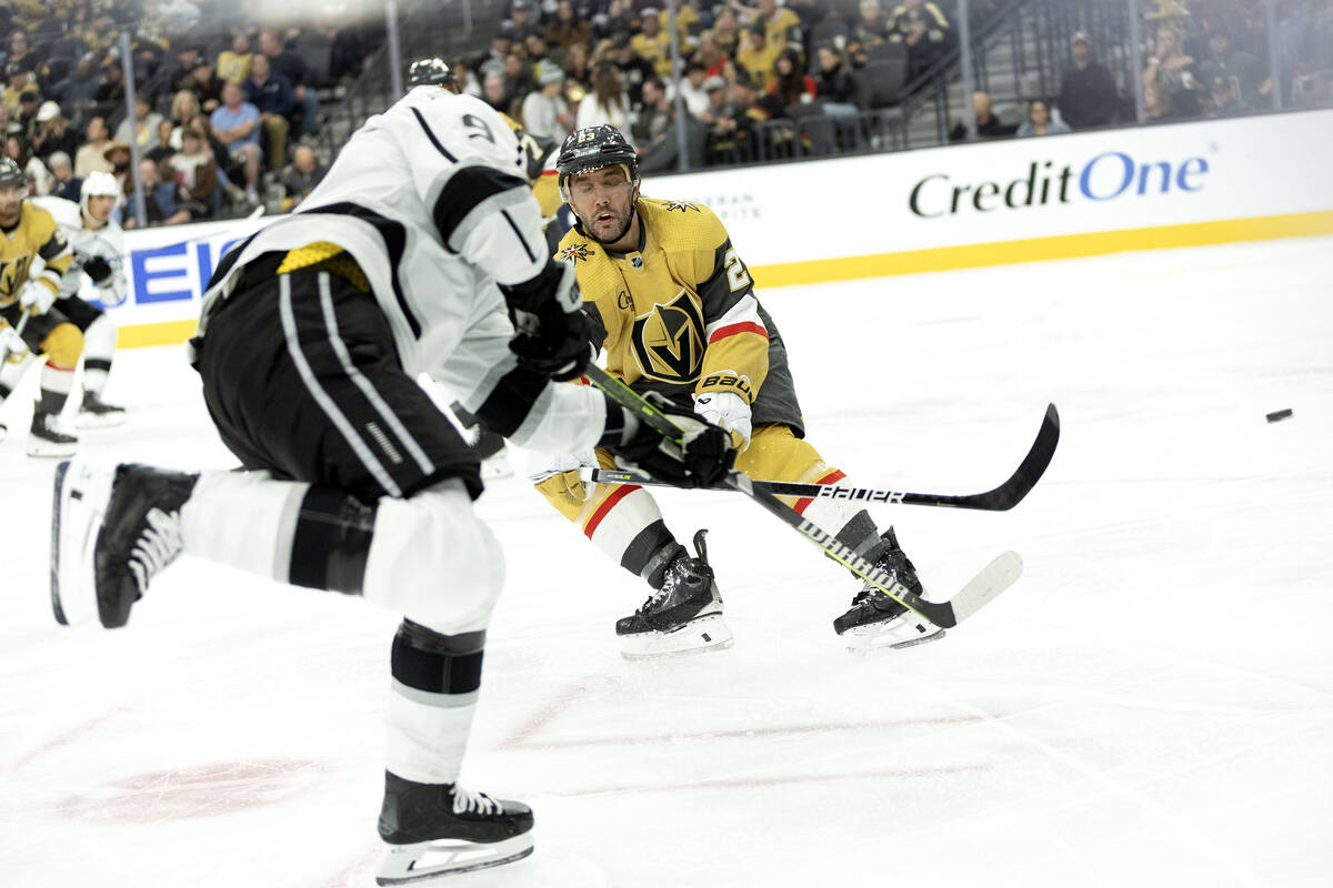 Golden Knights defenseman Alec Martinez (23) reaches to block a shot by Kings center Adrian Kem ...