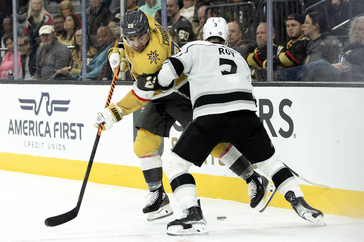 Golden Knights left wing William Carrier (28) and Kings defenseman Matt Roy (3) battle for the ...