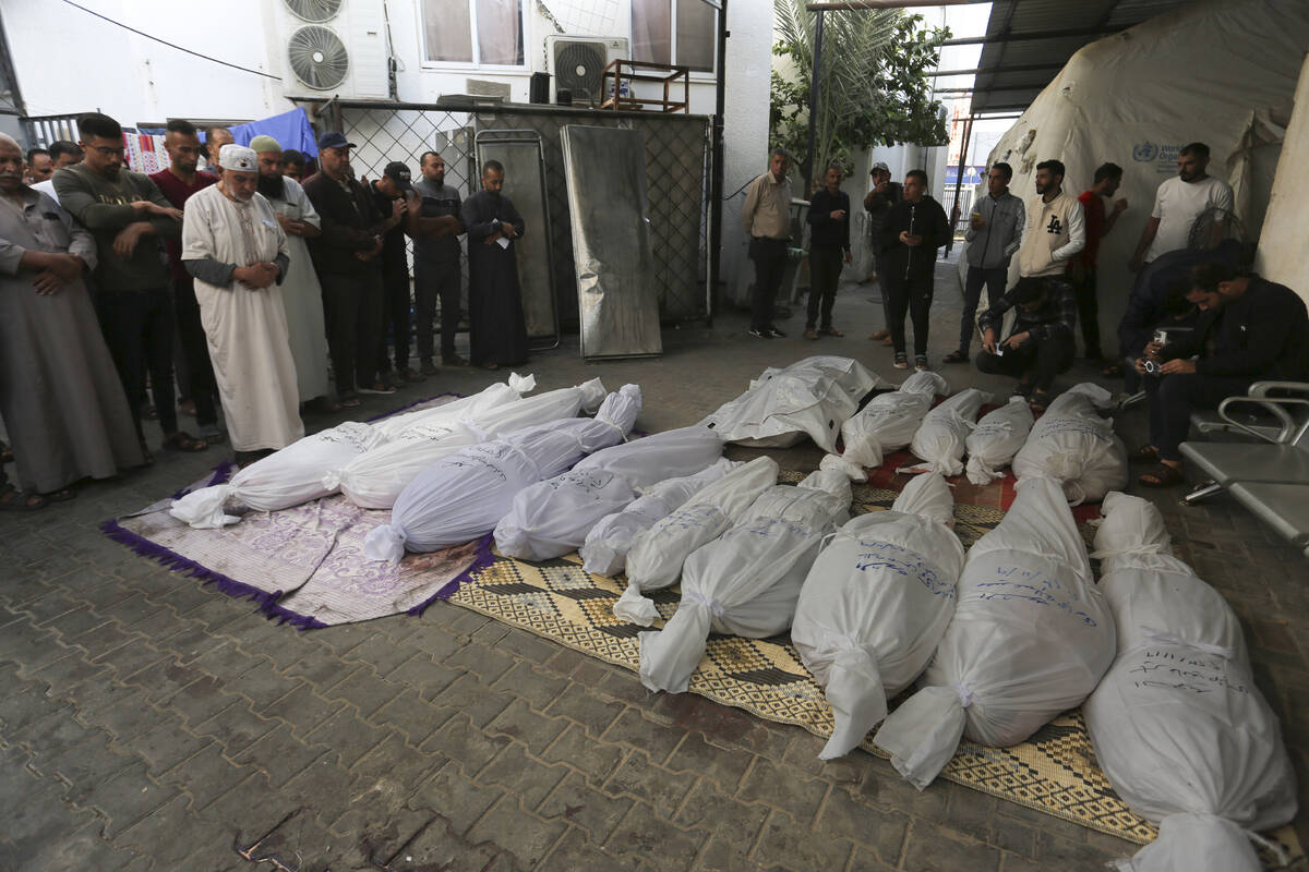 Palestinians pray by the bodies of the Hijazi family that was killed in the Israeli bombardment ...