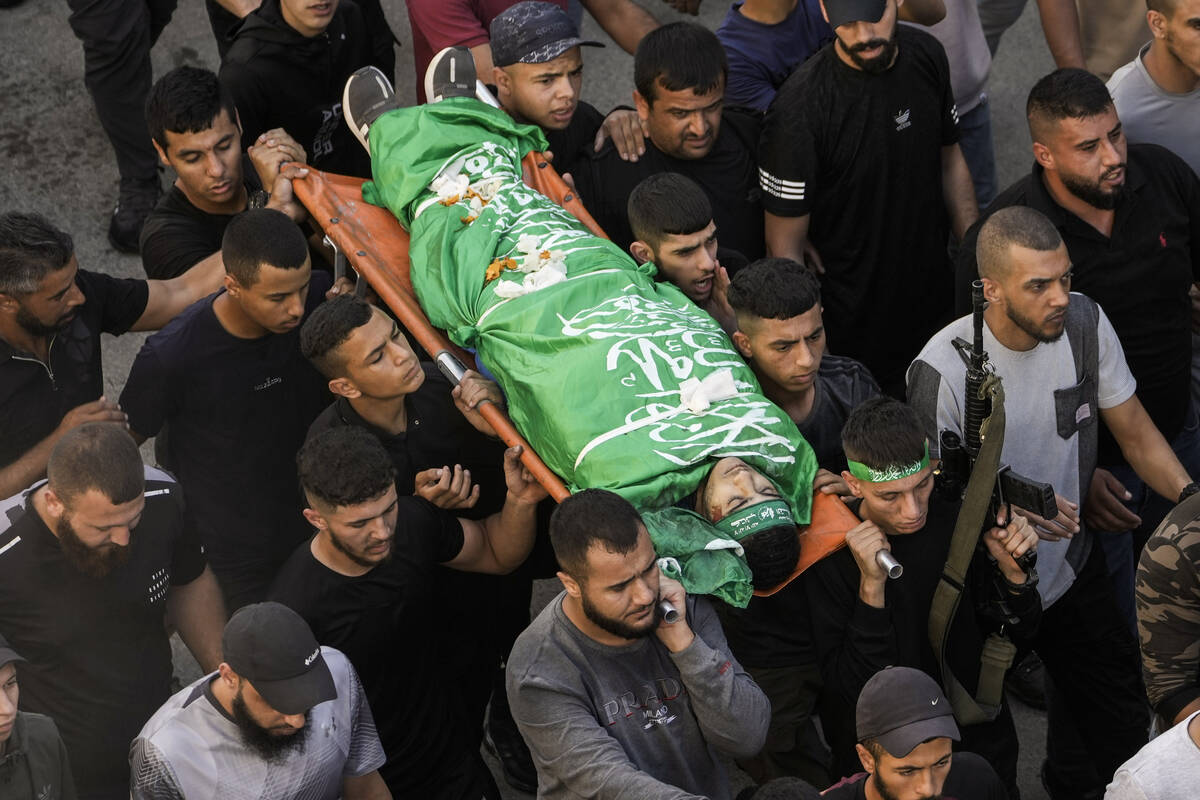 Palestinians carry the bodies of a militant killed in clashes during an Israeli military raid, ...